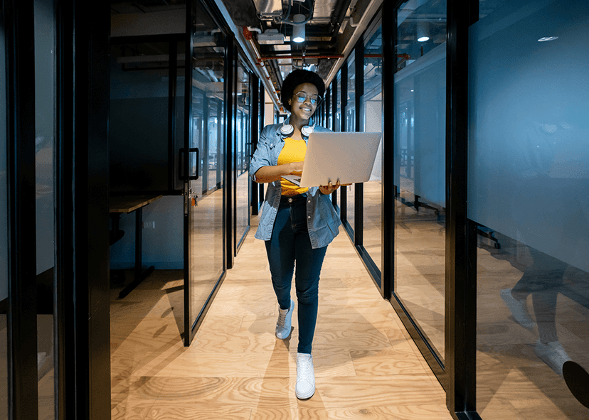 Woman IT manager walking office hall with laptop